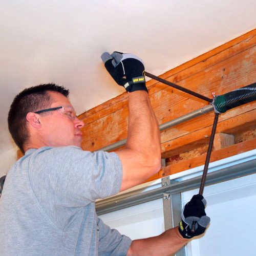 techincian winding a torsion spring on a garage door