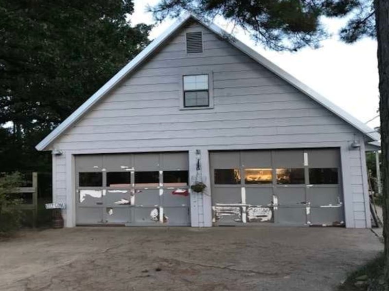 worn-out garage door with several signs of damage, including cracks, dents, and rust spots