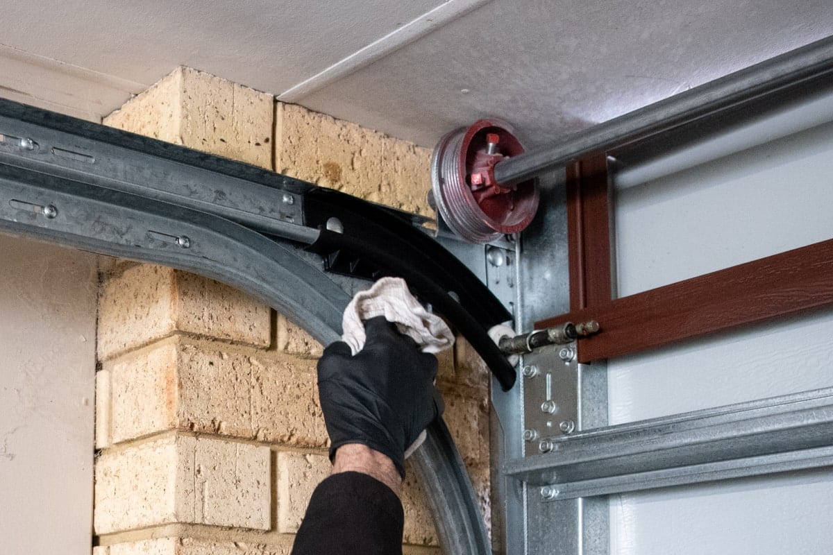 person wipes off garage door tracks