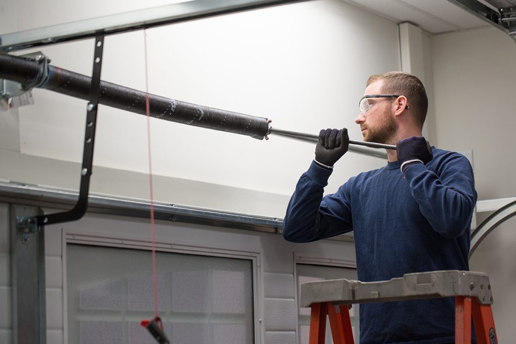 How To Replace Garage Door Springs? 1 person replacing garage door spring, holding the tube